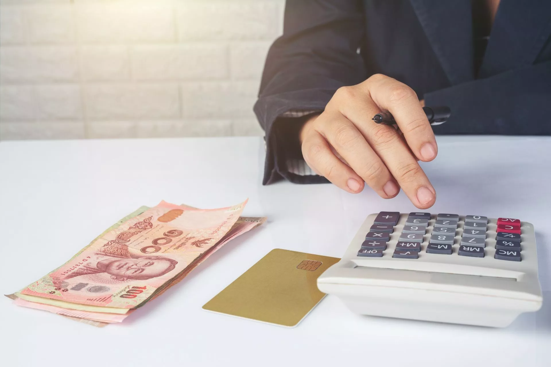 桌面上有計算機、現金與卡片，人物正在按計算機，呈現台中當鋪借款額度試算、借款成本評估與資金規劃情境