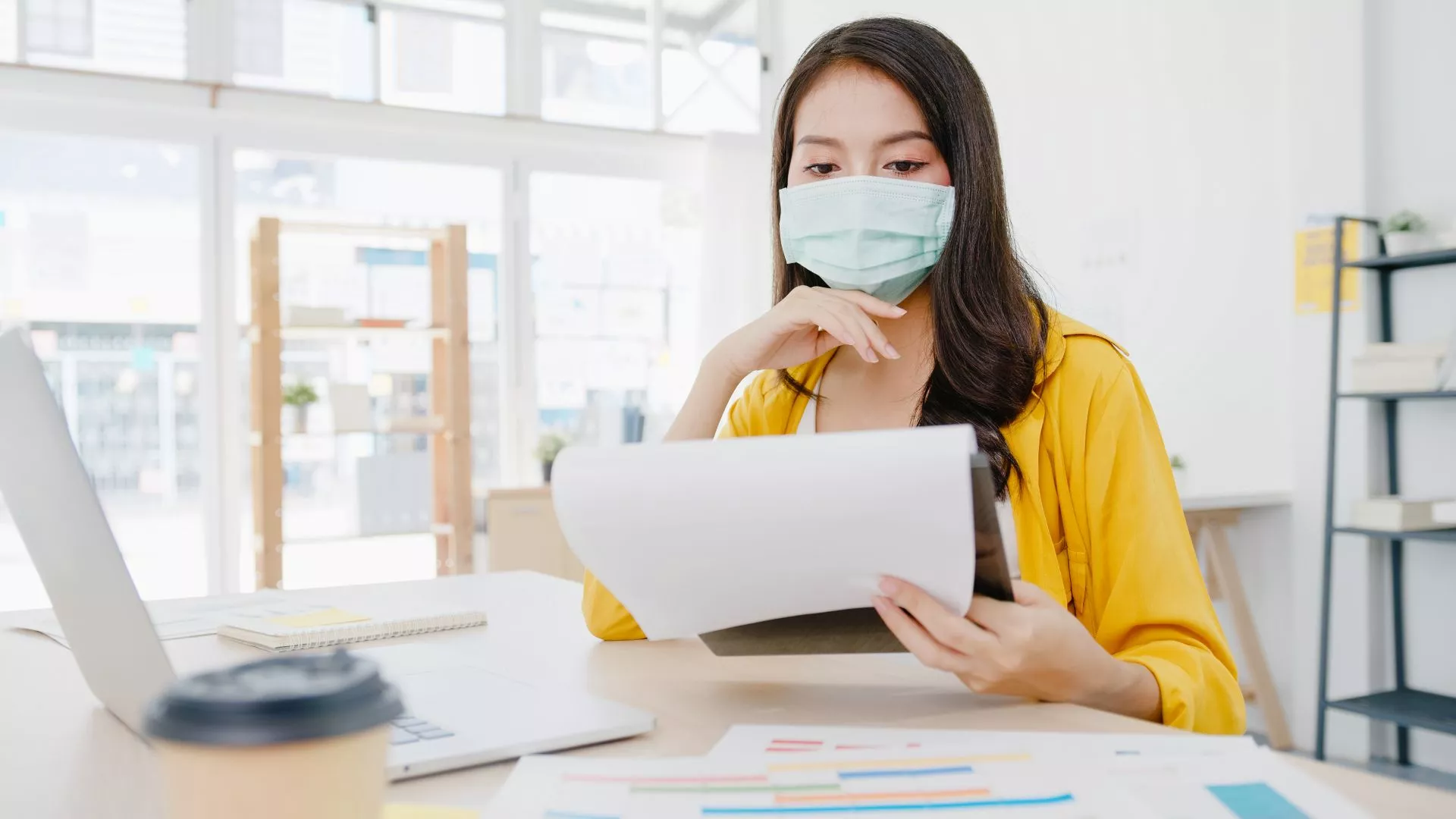 戴口罩女子在辦公室查看文件與資料，象徵台中機車借款免留車申請前的資料準備、文件審核與臨時資金周轉評估流程。
