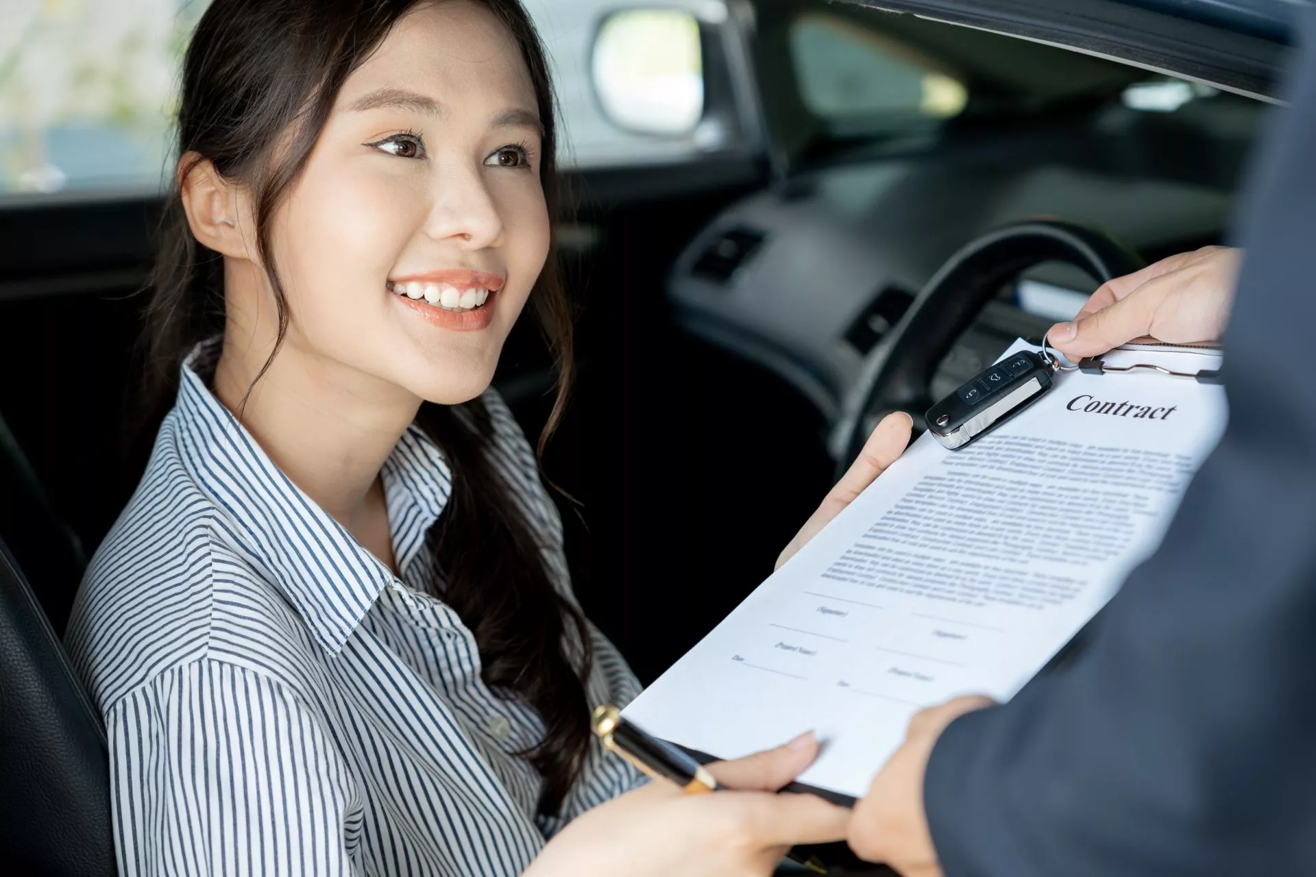 女子坐在車內與業務人員確認汽車借款合約並交付車鑰匙，象徵台中汽車借款免留車、車輛貸款申請與合約審核流程。