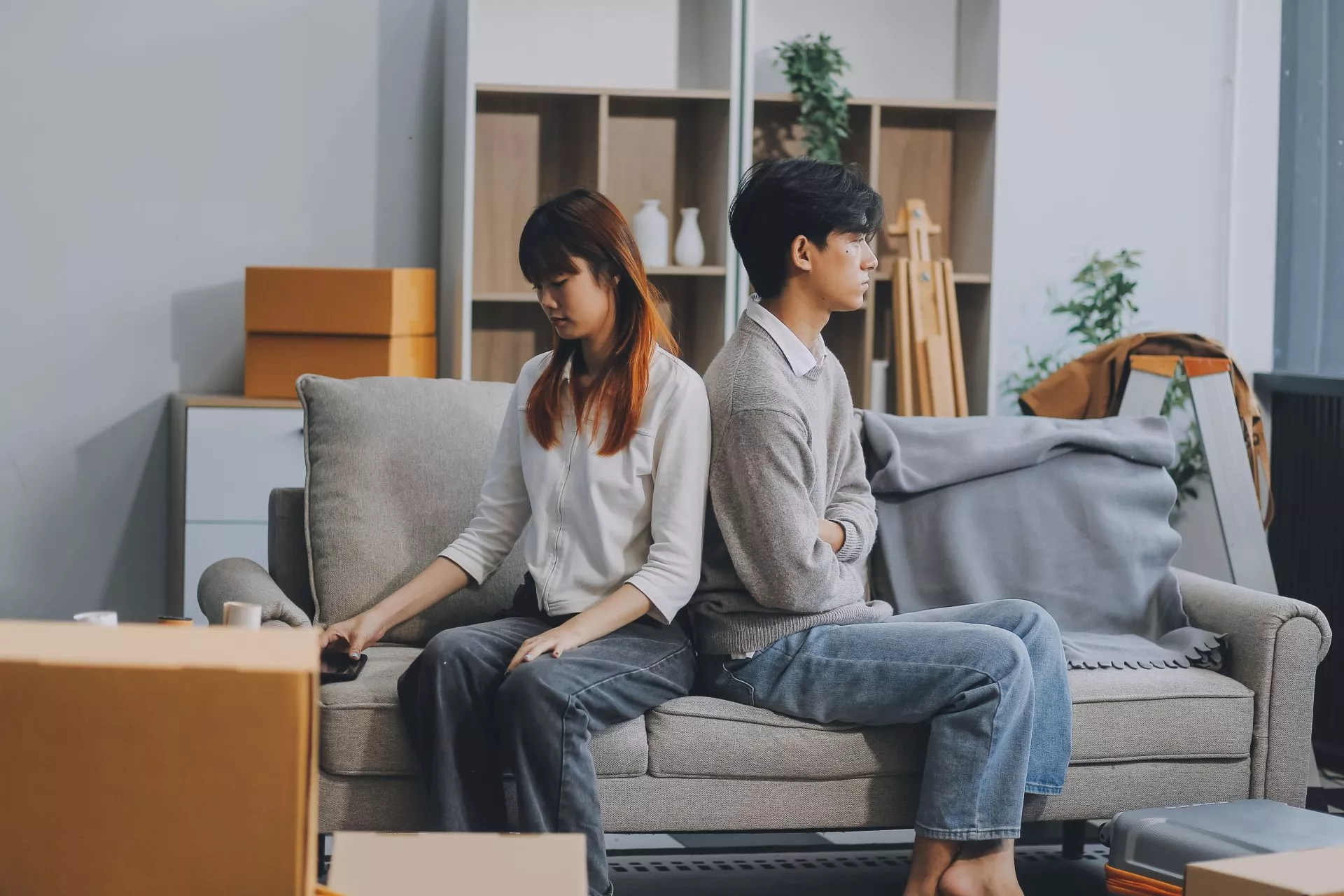 年輕夫妻坐在搬家紙箱旁神情低落，呈現薪水尚未入帳、房租到期、台中短期借款、房租週轉與台中當鋪借款評估情境。